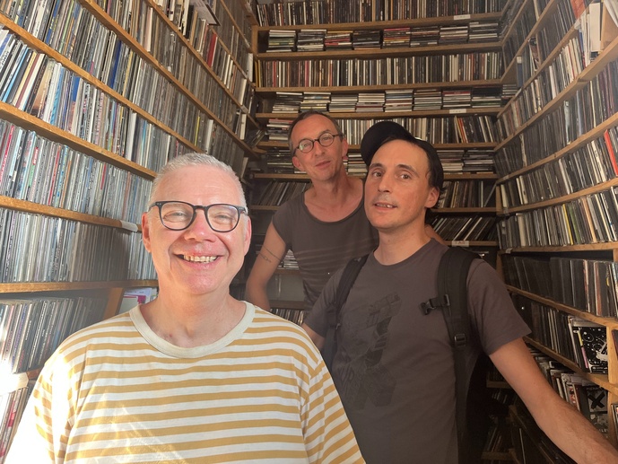 Loïc, casquette vissée sur la tête, aux côtés d’un bénévole et d’un salarié : tous trois utilisent encore des milliers de CD et de cassettes diffusés à l’antenne. © Loïc Couatarmanach.