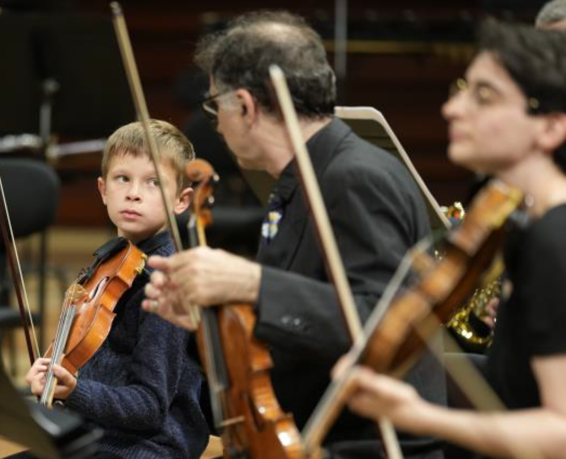Un jeune violoniste aux côtés de musiciens professionnels lors d’une répétition à la Maison de la Radio et de la Musique, dans le cadre du projet "Viva l’Orchestra !" © Christophe Abramowitz / Radio France