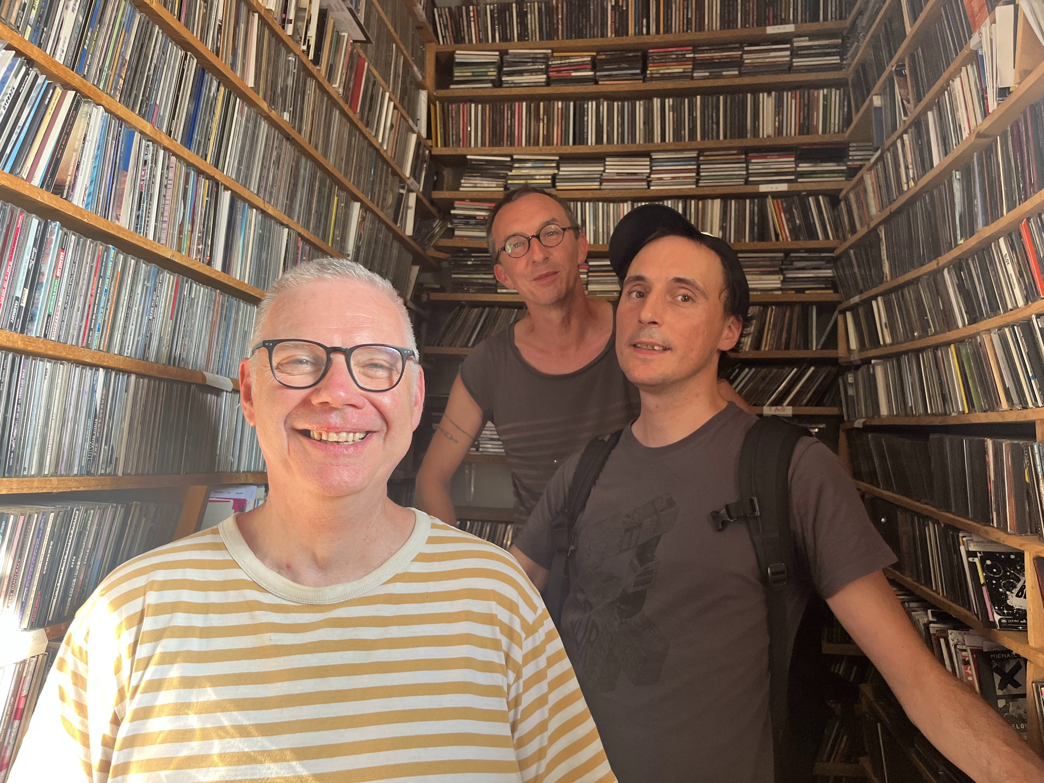 Loïc, casquette vissée sur la tête, aux côtés d’un bénévole et d’un salarié : tous trois utilisent encore des milliers de CD et de cassettes diffusés à l’antenne. © Loïc Couatarmanach.